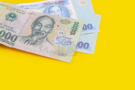Billetes dong vietnamitas sobre fondo amarillo.