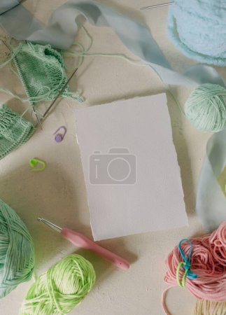 White card Mockup on light background, knitting threads in pastel colors, metal knitting needles