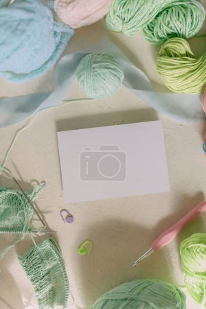 White card Mockup on light background, knitting threads in pastel colors, metal knitting needles