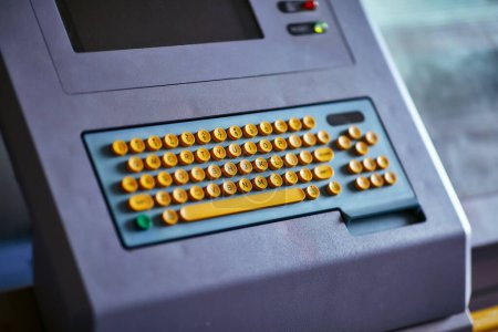 Photo for Built-in color keyboard with yellow mechanical buttons for the computer of a large industrial knitting machine with a built-in monitor next to it - Royalty Free Image