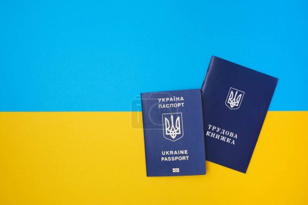 Photo for One Ukrainian employment history on the Ukrainian national flag in the top view. Translation: "Employment history". And Ukrainian national biometric passport - Royalty Free Image