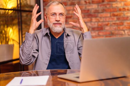 Photo for Worried aged man sit by laptop and try do make payment online . - Royalty Free Image