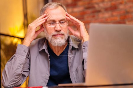 Photo for Worried aged man sit by laptop and try do make payment online . - Royalty Free Image