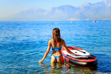 Photo for Woman sitting on sup board and enjoying peace and quiet outdoors . - Royalty Free Image