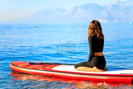 Photo for Woman sitting on sup board and enjoying peace and quiet outdoors . - Royalty Free Image