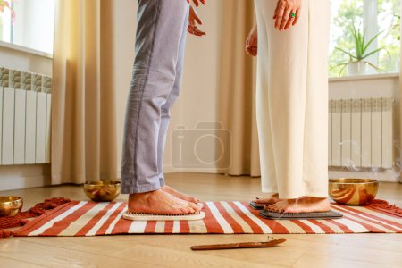 Téléchargez les photos : Couple amoureux matin yoga pratique avec clous sadhu. hommes et femmes pied sur le bureau en bois avec des ongles métalliques pointus. - en image libre de droit