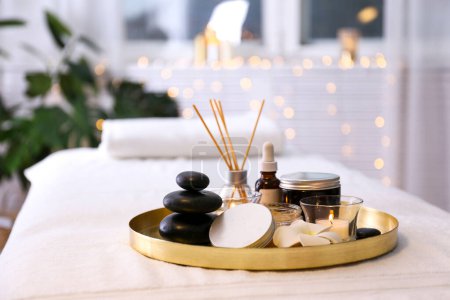 Stone therapy attributes for cosmetic procedures on a massage table. Symbolic objects for spa salon. Close up, copy space for text, top view, bokeh lights on the background.