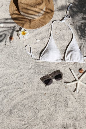 Foto de Vibras de verano. Sombrero de paja, traje de baño y gafas de sol en una playa de arena.. Piso tendido, espacio para copiar, vista superior, fondo. - Imagen libre de derechos