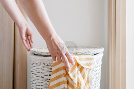 Photo for Female hand put long-sleeved t-shirt in laundry basket. High quality photo - Royalty Free Image