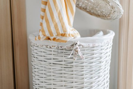 Photo for Female hand put long-sleeved t-shirt in laundry basket. High quality photo - Royalty Free Image