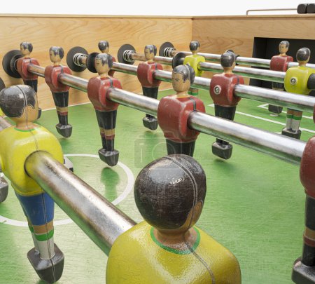 Téléchargez les photos : Une table de baby-foot vintage en bois avec figurines détaillées en métal jaune et rouge sur fond de studio blanc isolé - rendu 3D - en image libre de droit