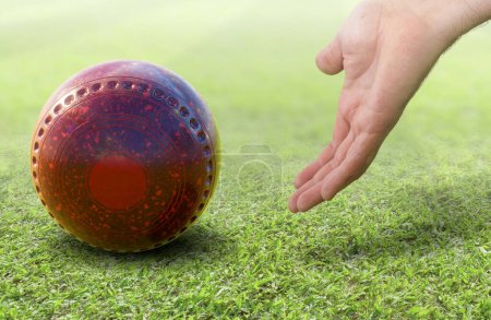 Photo for A male hand bowling and releasing a red lawn bowling ball on a green lawn grass surface -3D render - Royalty Free Image
