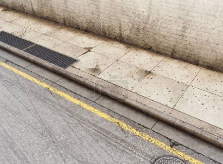 Téléchargez les photos : Une section d'une rue vide usée et grincheuse, trottoir pavé et mur de briques noires - rendu 3D - en image libre de droit