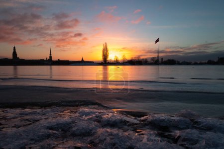 Téléchargez les photos : Un magnifique paysage hivernal au lever du soleil à Riga, capitale de la Lettonie, avec la rivière gelée Daugava. Paysage urbain coloré de l'Europe du Nord. - en image libre de droit