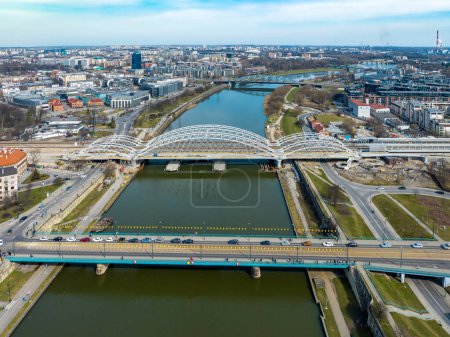 Five bridges on Vistula River in Krakow, Poland. Aerial view. Boulevards with waking people. New double railway tied-arc bridge an Kraow-Zabocie railroad station still in construction
