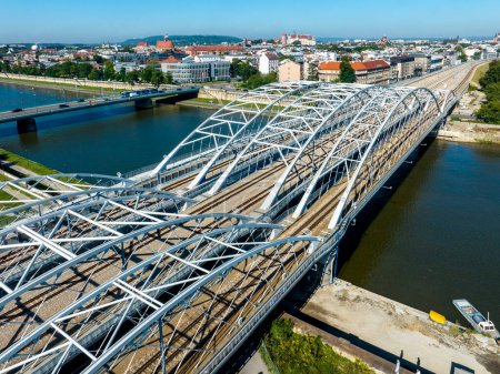 Téléchargez les photos : Nouveau pont ferroviaire à triple arc à quatre voies sur la Vistule à Cracovie, en Pologne. Un autre pont avec des voitures et un tramway. Vieille ville avec château de Wawel en arrière-plan. Vue aérienne du drone - en image libre de droit