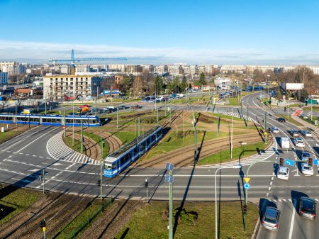 Photo for Traffic circle Rondo Czyzynskie in Krakow, Poland, with tramway crossing, four trams, three lane city roads, bicycle lanes and cars. Aerial drone view. Urban skyline - Royalty Free Image