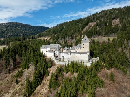 Medieval Moosham Castle in Unternberg near Lungau in Austria in Salzburg area. Build in 13th century. A stone fortress with a tower on a high hill surrounded by mountains covered with forests