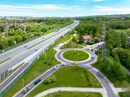 Three lane motorway A4 in Krakow, Poland. Entrance ramp and exit ramp with a traffic circle, cars and noise barriers. Aerial view
