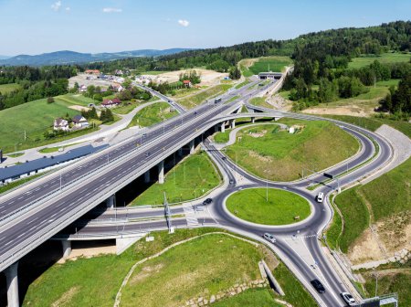 Poland. New Zakopianka multilane highway with a tunnel, multilevel spaghetti junction, crossroad with traffic circles, viaducts, entrance and exit ramps and traffic near Skomielna Biala. Aerial wiew