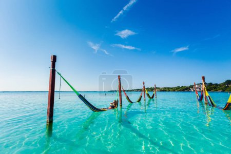 Photo for Beautiful white female tourist relaxing in a hammock in Laguna Bacalar in Mexico during kayak trip. - Royalty Free Image
