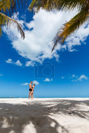 Foto de Hermosa pareja feliz joven en la playa de Progreso, México durante el día soleado. Playa blanca y cielo azul. - Imagen libre de derechos