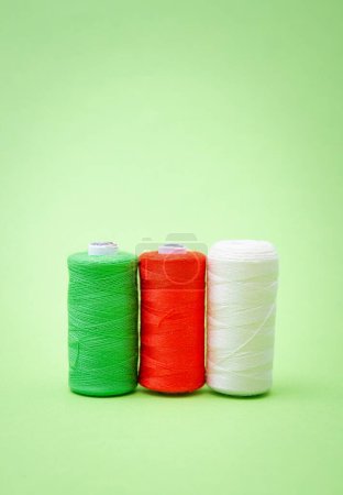 Téléchargez les photos : Différentes bobines de fil de coton à coudre de différentes couleurs drapeau italien sur fond vert - en image libre de droit