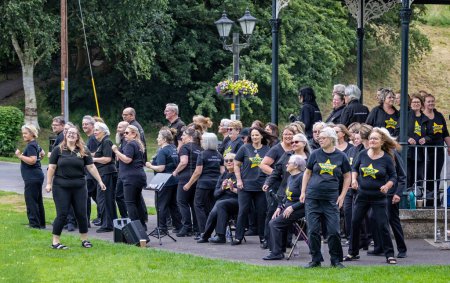 Photo for Large local rock choir performing enthusiastically in Warminster bandstand in Wiltshire, UK on 1 July 2023 - Royalty Free Image