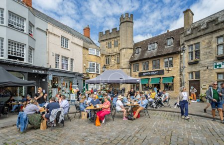 Foto de Ocupados cafés al aire libre frente al Penniless Porch el sábado en Market Place, Wells, Somerset, Reino Unido el 29 de julio de 2023 - Imagen libre de derechos