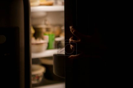 Photo for Woman hand by the open refrigerator at night - Royalty Free Image