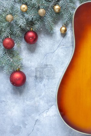Photo for Acoustic guitar and  fir tree branches with red and golden Christmas  balls on light background. - Royalty Free Image