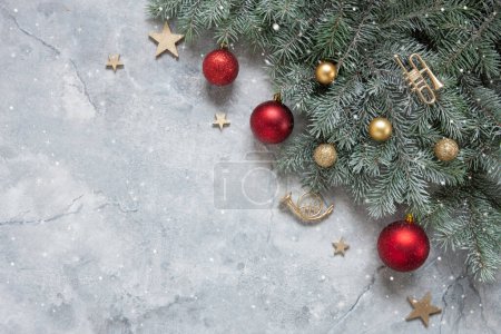 Téléchargez les photos : Composition festive de Noël et du Nouvel An avec branches de sapin des neiges, trompette jouet, boules de Noël rouges et dorées sur le fond de marbre - en image libre de droit