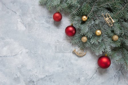 Téléchargez les photos : Composition festive de Noël et du Nouvel An avec branches de sapin des neiges, trompette jouet, boules de Noël rouges et dorées sur le fond de marbre - en image libre de droit