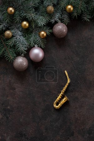 Foto de Copia de saxofón dorado en miniatura, ramas de abeto y bolas rosas navideñas. Concepto de Navidad y Año Nuevo. Vista superior, primer plano - Imagen libre de derechos