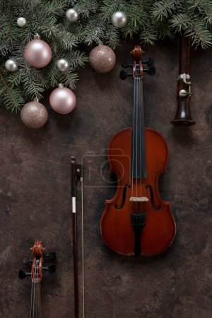 Photo for Old violin and flute with fir-tree branches with Christmas decor. Christmas and New Year's concept. Top view, close-up on dark concrete background - Royalty Free Image