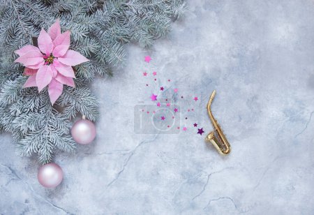 Foto de Copia miniatura de saxofón dorado, ramas de abeto nevado, suave flor de poinsettia y bolas de color rosa navideño. Concepto de Navidad y Año Nuevo. Vista superior, primer plano - Imagen libre de derechos