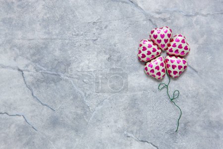 Foto de Primer plano de chocolates en forma de corazón en envoltura, doblado en flor. Fondo, vista superior, espacio para copiar - Imagen libre de derechos