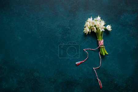 Magnifique bouquet frais de la première forêt printanière avec des fleurs de martisan cordon rouge et blanc - symbole traditionnel du premier jour de printemps sur fond bleu
