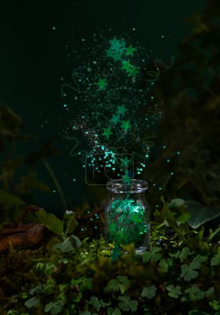 Foto de Verde estrella forma brillante confeti fuegos artificiales de pequeña botella de vidrio en musgo verde con trébol. 17 Marzo Día de San Patricio concepto mágico - Imagen libre de derechos