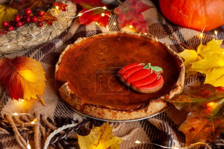 Photo for Traditional homemade festive pumpkin pie on cosy checkered plaid. - Royalty Free Image