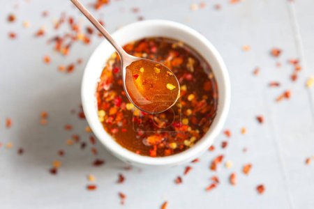Photo for Spicy or hot chilli honey in the spoon and the bowl close up - Royalty Free Image