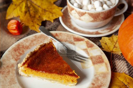 Photo for Traditional American Homemade pumpkin pie on a rustic table with cosy autumn decorations and maple leaves - Royalty Free Image