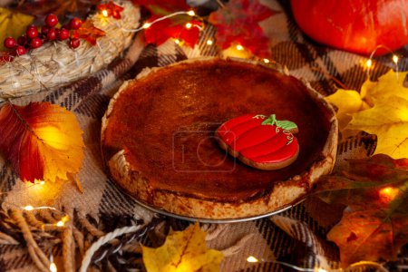 Foto de Pastel tradicional de calabaza casera estadounidense sobre una mesa rústica con acogedoras decoraciones otoñales y hojas de arce - Imagen libre de derechos