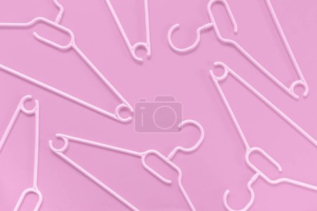Téléchargez les photos : Cintres en plastique sur fond rose. Concept vente, boutique, occasion, commerce en ligne, plateforme de revente de marque - en image libre de droit