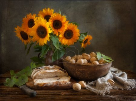 Foto de Homemade bread, walnuts, sunflowers and vintage ceramic kitchenware on an old wooden table. Artistic Still Life in Vintage Style. - Imagen libre de derechos