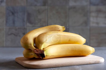 Photo for Fresh organic bananas on a kitchen board lie on the table. Close-up, selective focus - Royalty Free Image