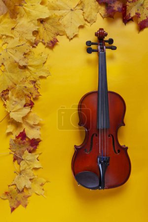 Téléchargez les photos : Old violin on yellow autumn maple leaves background. Top view, close-up. - en image libre de droit
