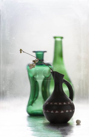 Photo for Still life with transparent green colored glass bottles and vase - Royalty Free Image