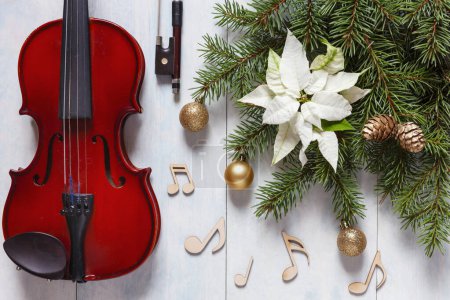 Téléchargez les photos : Vieux violon, panneaux de notes en bois et branches de sapin avec décor de Noël et poinsettia blanc. Noël, le concept du Nouvel An. Vue de dessus, gros plan - en image libre de droit