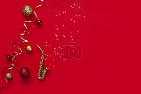 Téléchargez les photos : Fête de Noël rouge et fond du Nouvel An avec Miniature copie de saxophone doré et décor de Noël. Vue du dessus, espace de copie, plan - en image libre de droit